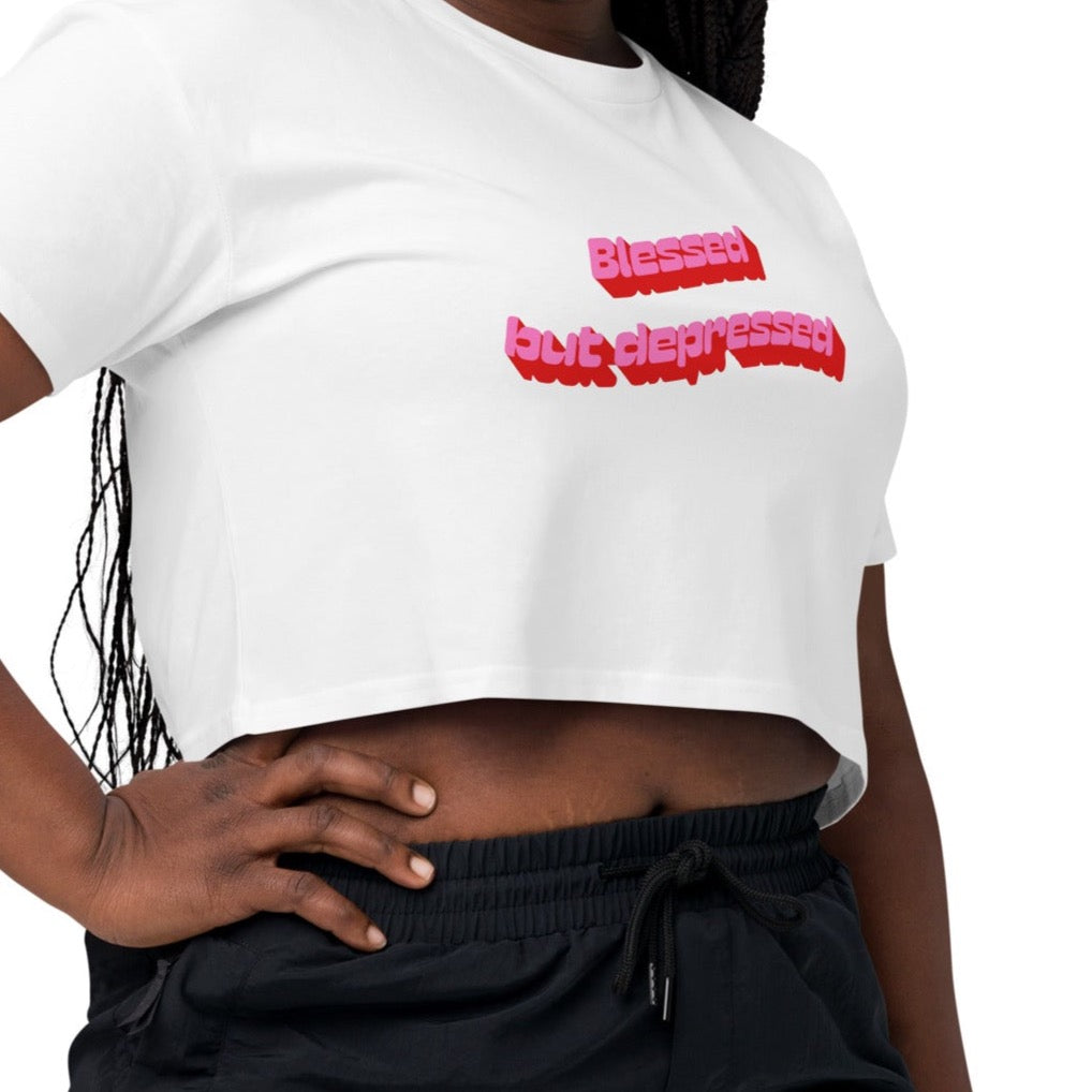 A woman wearing white crop top that says blessed but depressed by cool girl candles
