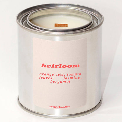 a paint tin candle that says "heirloom" made by cool girl candles and is a tomato scented candle for summer made with coconut soy wax and a wood wick.